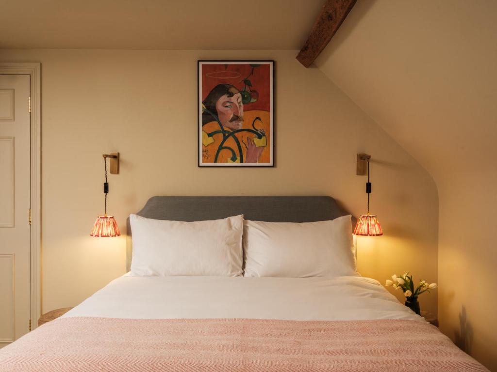 a bedroom with a white bed with two lights at The Bell & Crown in Zeals
