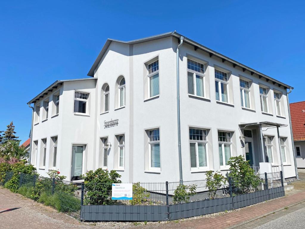 a white building with a fence in front of it at Haus Seestern in Thiessow