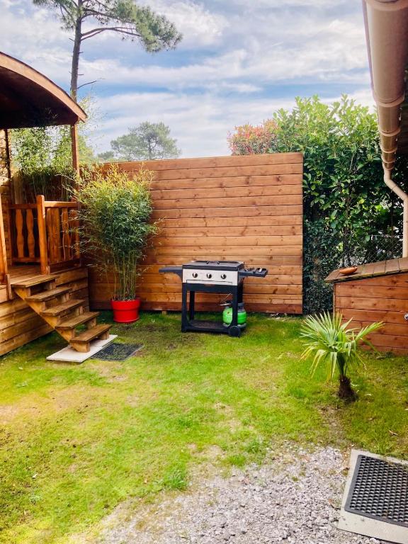 - un barbecue dans une arrière-cour avec une clôture en bois dans l'établissement Roulotte atypique à l'Océan, à Labenne