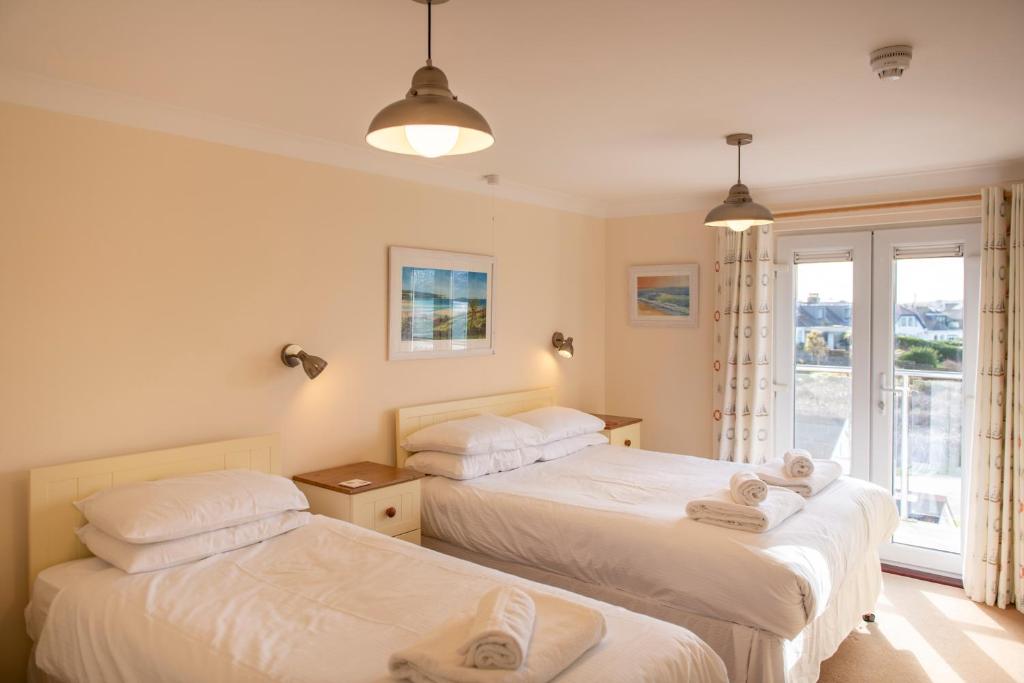 two beds in a room with a window at Sandy Bay Apartment, St Ives Bay, Hayle in Hayle