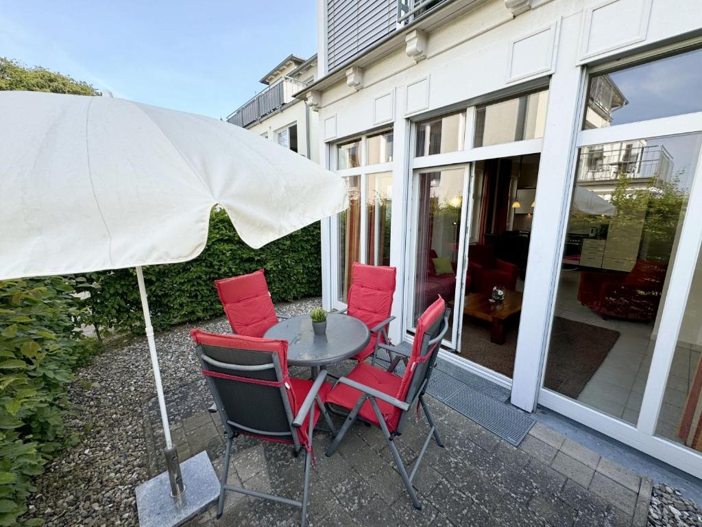 einen Tisch mit roten Stühlen und einem Regenschirm in der Unterkunft Haus Möwe I Whg 02 mit Terrasse in Ostseebad Sellin
