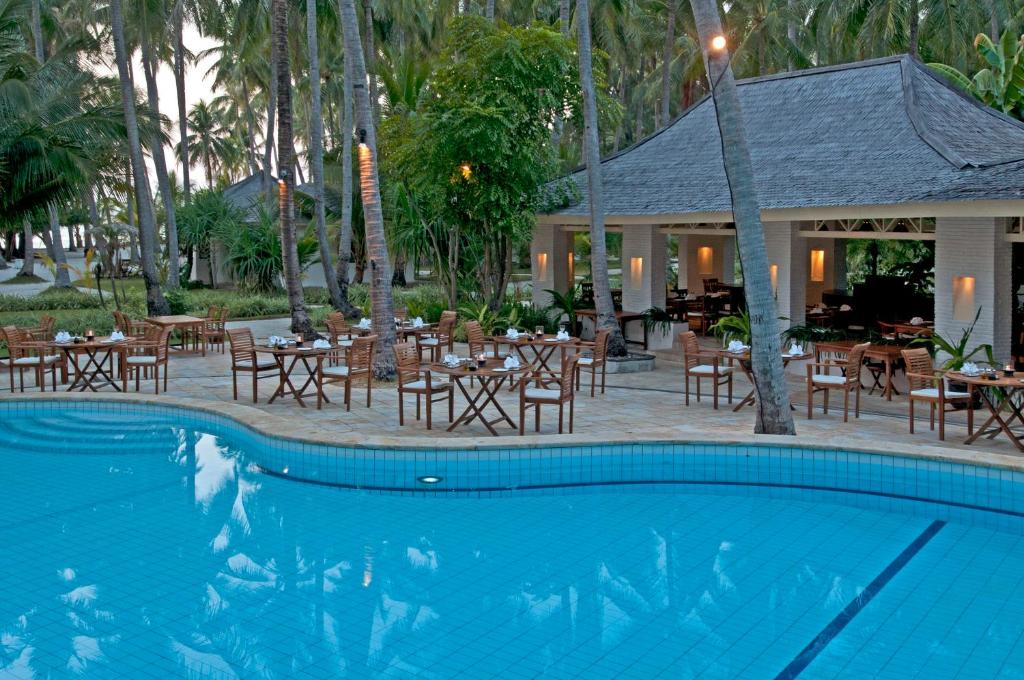 a swimming pool with tables and chairs and a restaurant at Kura Kura Resort in Karimunjawa
