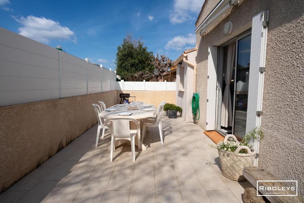 une table et des chaises sur le patio d'une maison dans l'établissement Maison 6 personnes à 300m de la mer, à Vias