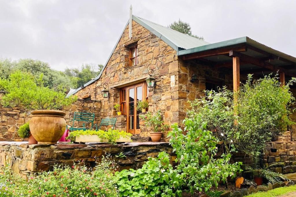 a small stone house with a window and plants at Stonehaven Cottage in Machadodorp