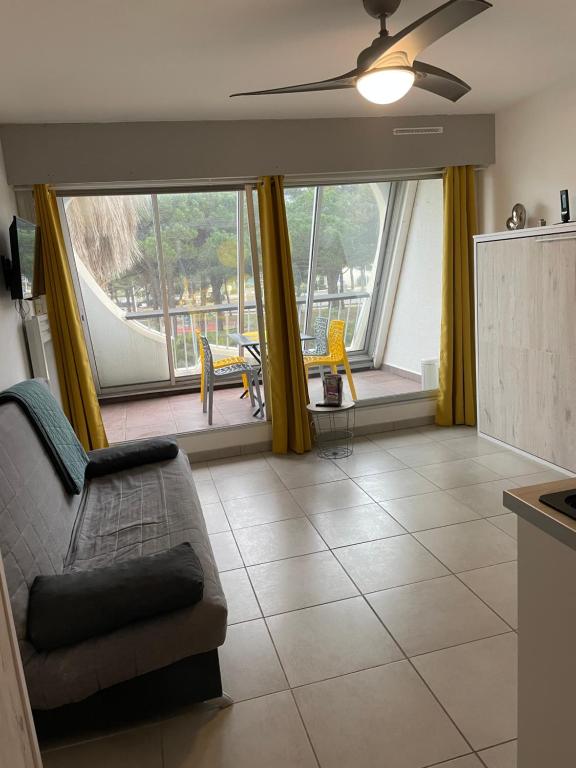 - un salon avec un canapé et de grandes fenêtres dans l'établissement Studio cabine L Escale Plage, au Grau-du-Roi