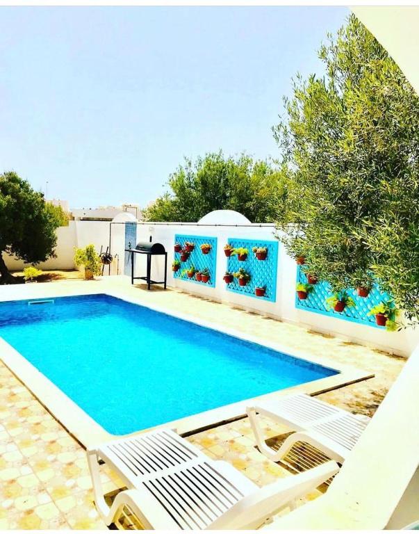 a swimming pool with two white chairs next to it at Villa Jasmin in Midoun