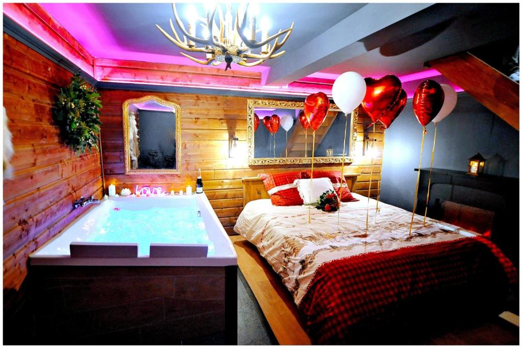 a bedroom with a tub with a bed and balloons at Le Chalet romantique, SPA XXL, Écran cinéma, Lit king size, cascade d'eau in Bourgoin