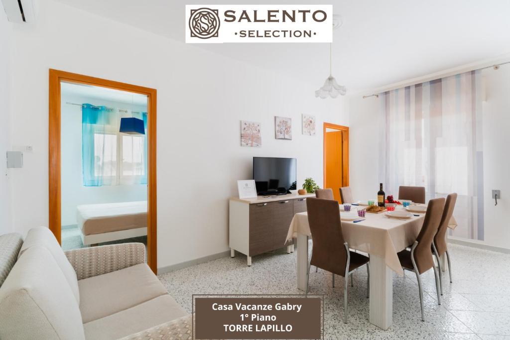 トッレ・ラピッロにあるCase Vacanze Gabry - Salento Selectionのテーブルと椅子のあるリビングルームとダイニングルーム