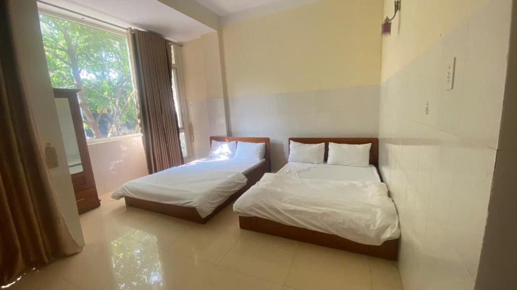 due letti in una stanza con finestra di nhà nghỉ thu hiền a Buôn Ma Thuột