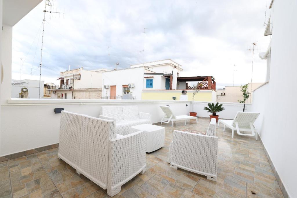 een balkon met witte stoelen en een bar bij Casa Indaterr in Mola di Bari