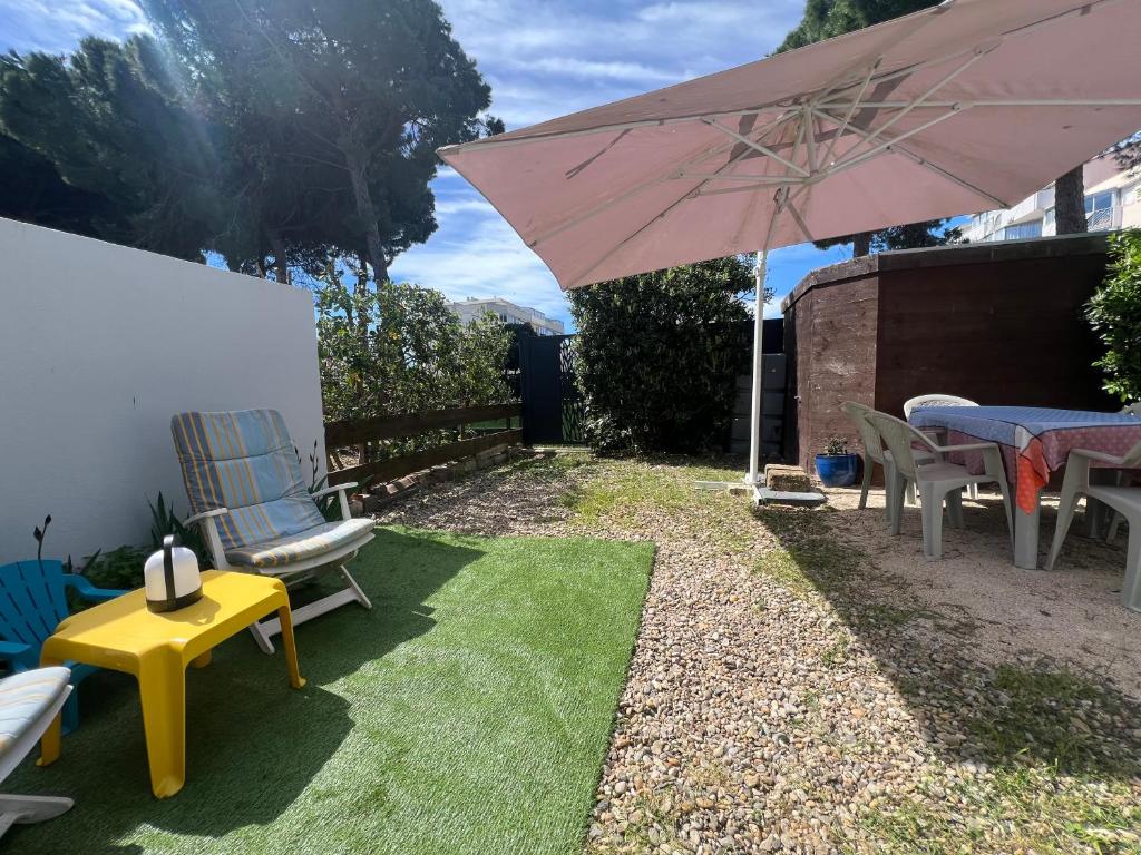 un patio avec une table, des chaises et un parasol dans l'établissement Sol-y-Days Baronnets, rez-de-chaussée avec grand jardin proche centre et plages, au Grau-du-Roi
