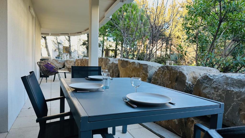 - une table bleue avec des assiettes et des verres à vin sur la terrasse dans l'établissement Oppidum Clim et Parking avec Terrasse de 30 m2 YourHostHelper, à Lattes