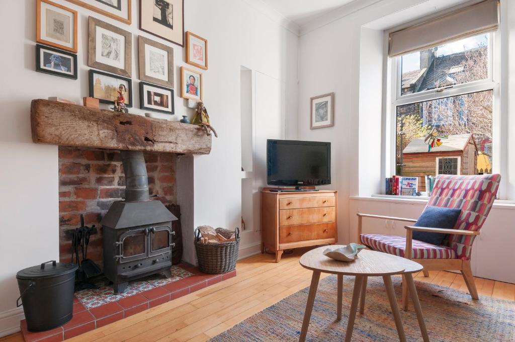 een woonkamer met open haard en tv bij Cozy with Character Vibrant Cottage Style Flat at Leith Links Park in Edinburgh
