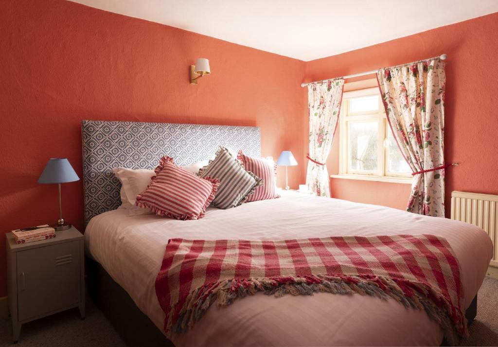 Schlafzimmer mit einem Bett mit roten Wänden und einem Fenster in der Unterkunft Palace Garden Cottage in Bishop Auckland