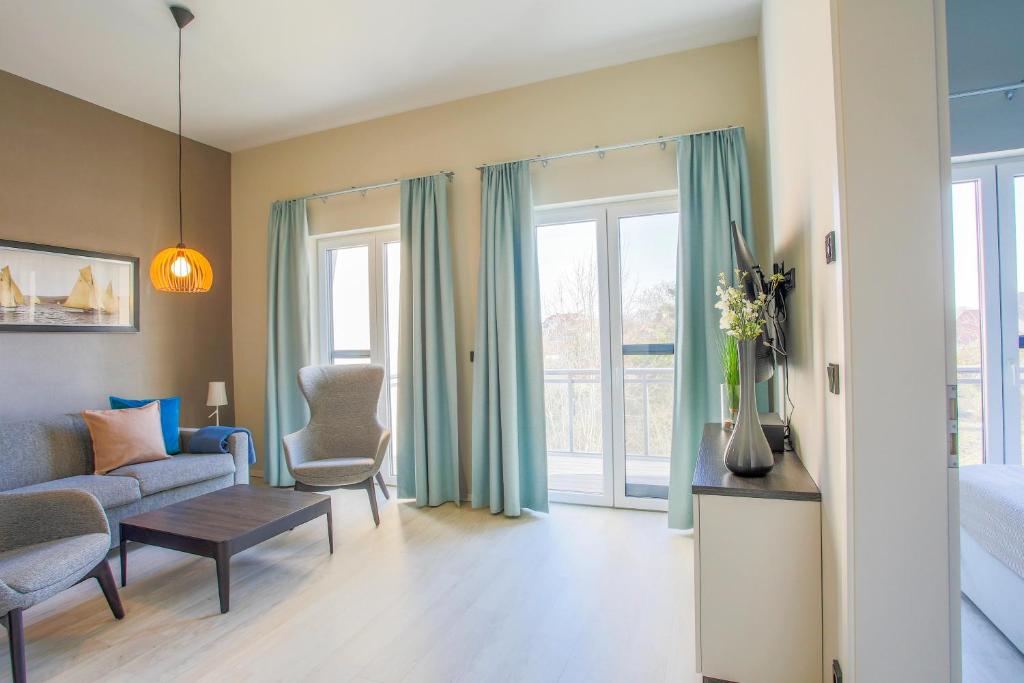 a living room with a couch and a bed and windows at Marco Polo Suite - Komfort und Erholung zwischen Ostsee und Bodden in Wustrow