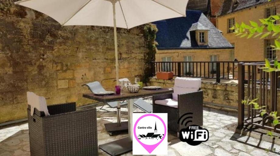 L'Appartement du "Coup de Coeur de Sarlat" في سارلا لا كانيدا: فناء فيه مظلة وطاولة وكراسي