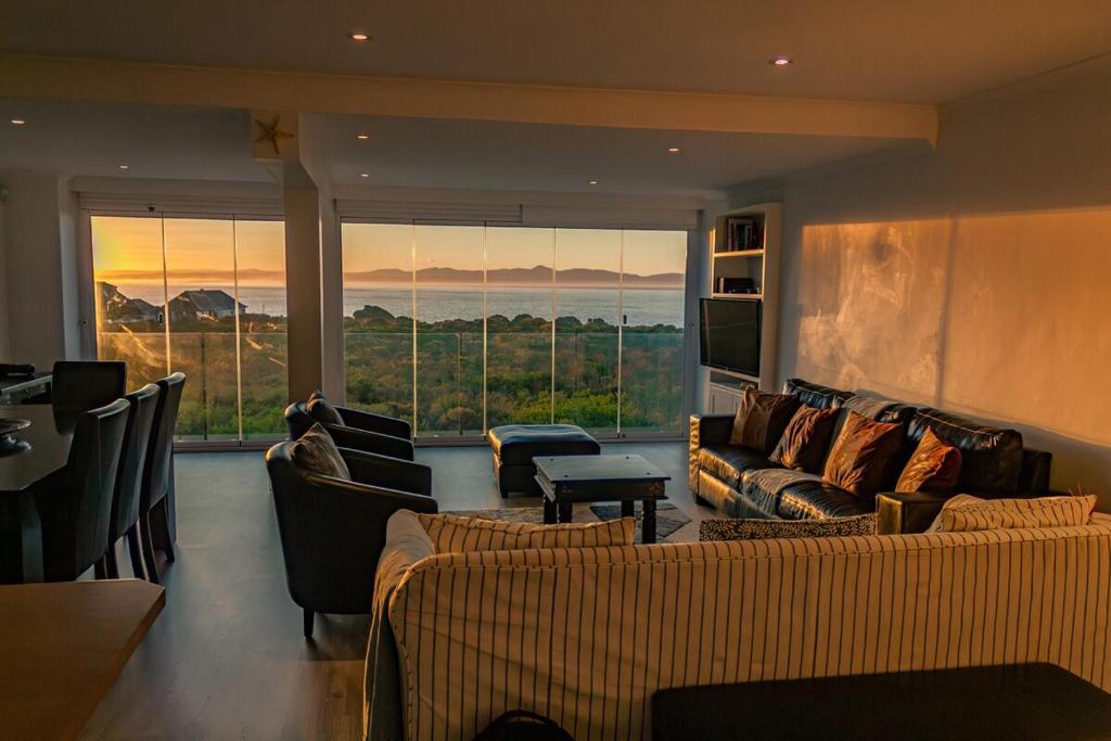 a living room with couches and chairs and a large window at Seaside Serenity: Tranquil Oceanview Retreat in Hermanus