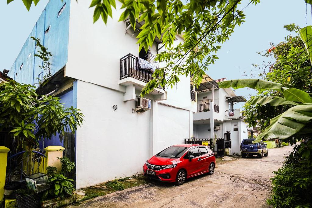 a red car parked next to a white building at OYO Life 92046 Garuda Residence in Palembang