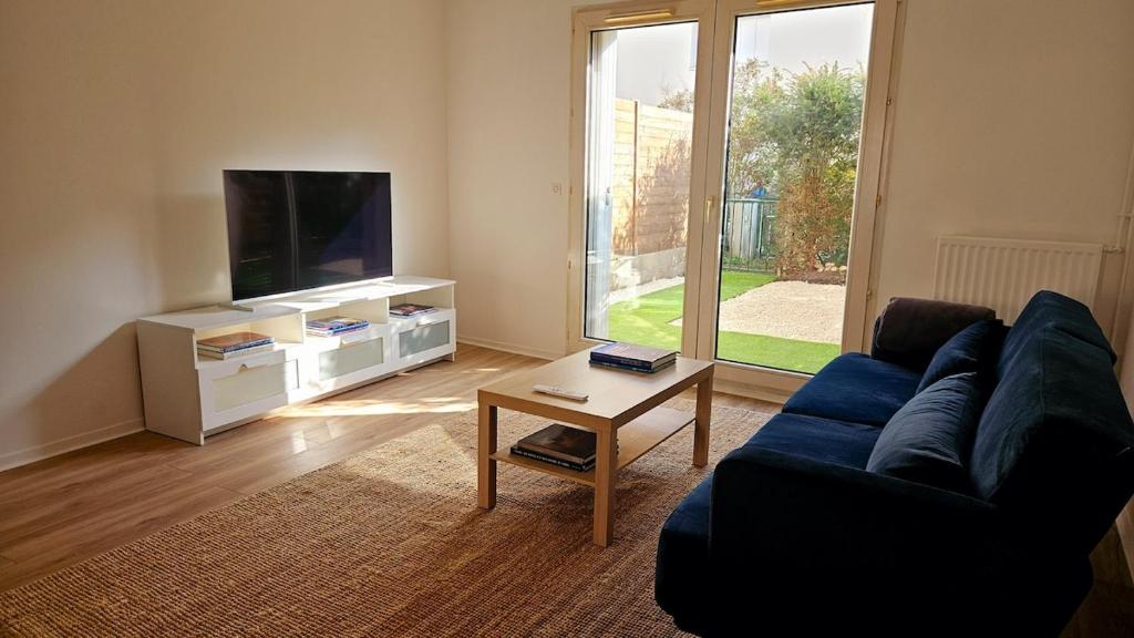 un salon avec un canapé bleu et une télévision dans l'établissement Paul Eluard - Maison au calme parking centre Tours, à Tours