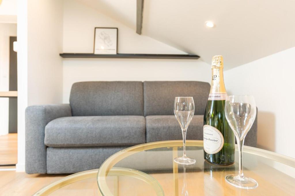 - une bouteille de champagne et 2 verres à vin sur une table dans l'établissement Nid douillet sous les combles, à Châlons-en-Champagne