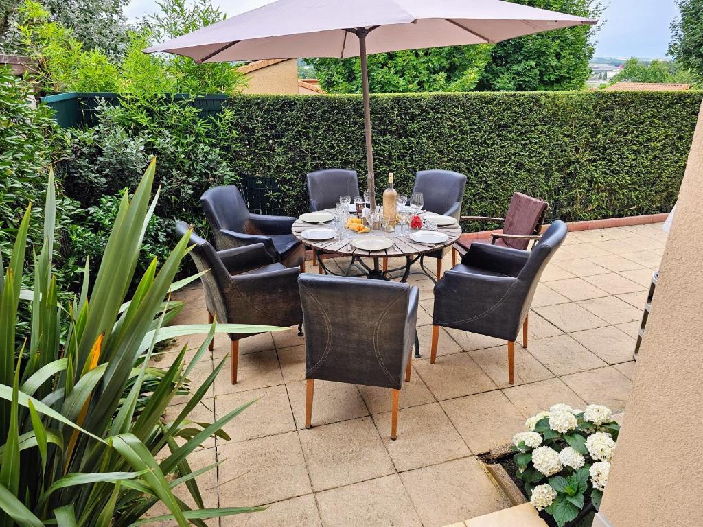 a table with chairs and an umbrella on a patio at Terrasse de Malissol in Vienne