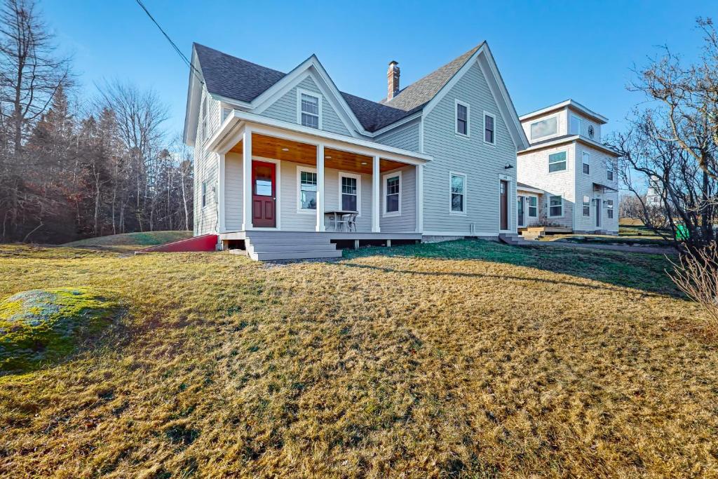 a white house with a red door on a yard at Lobster Cove Retreat in Prospect Harbor