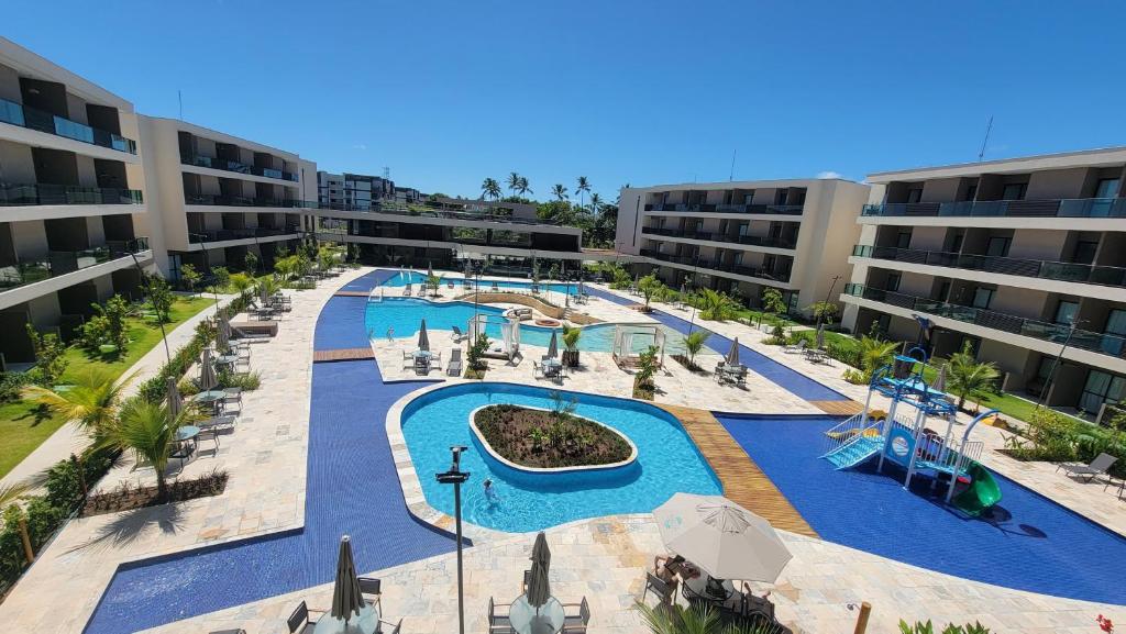 an apartment complex with a pool and a water park at Malia Beach Experience - Muro Alto - Vista piscina central - Flat 205C in Ipojuca