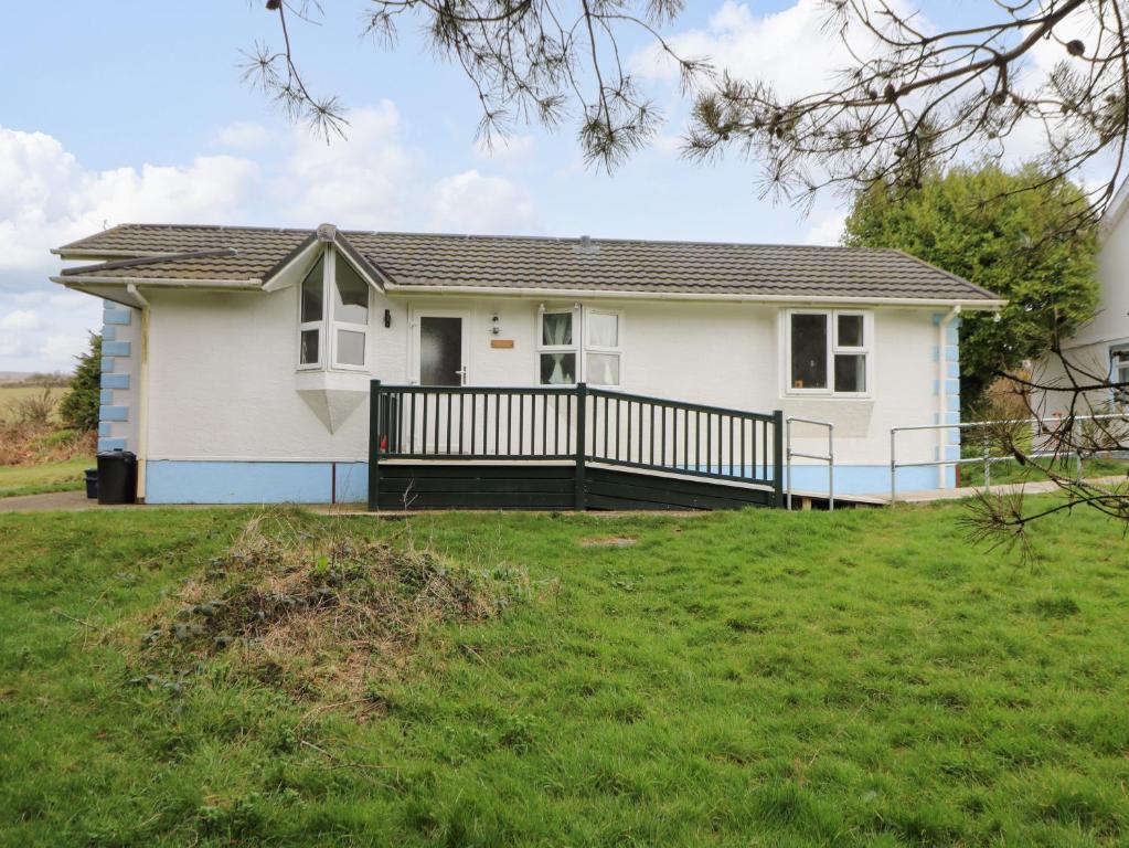 a white house with a porch and a yard at Nanny Jill's Cabin in Penrydd