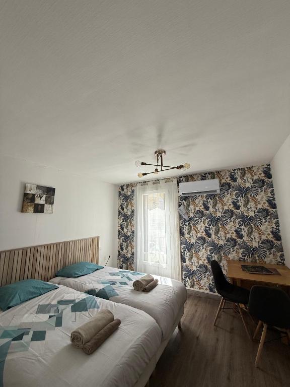 une chambre avec deux lits et un bureau et une fenêtre dans l'établissement Au pied des Thermes, à Amélie-les-Bains-Palalda