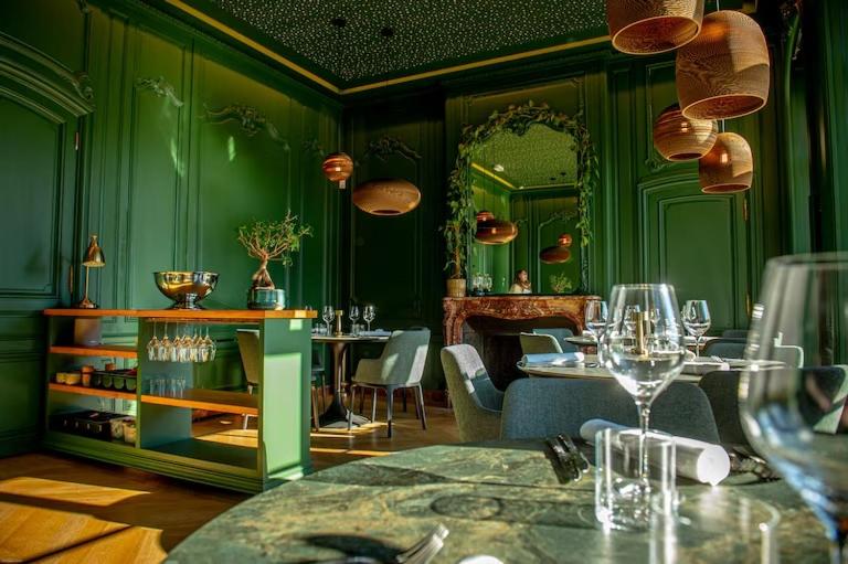 a restaurant with green walls and tables and wine glasses at Le Petit Château Peltzer in Verviers