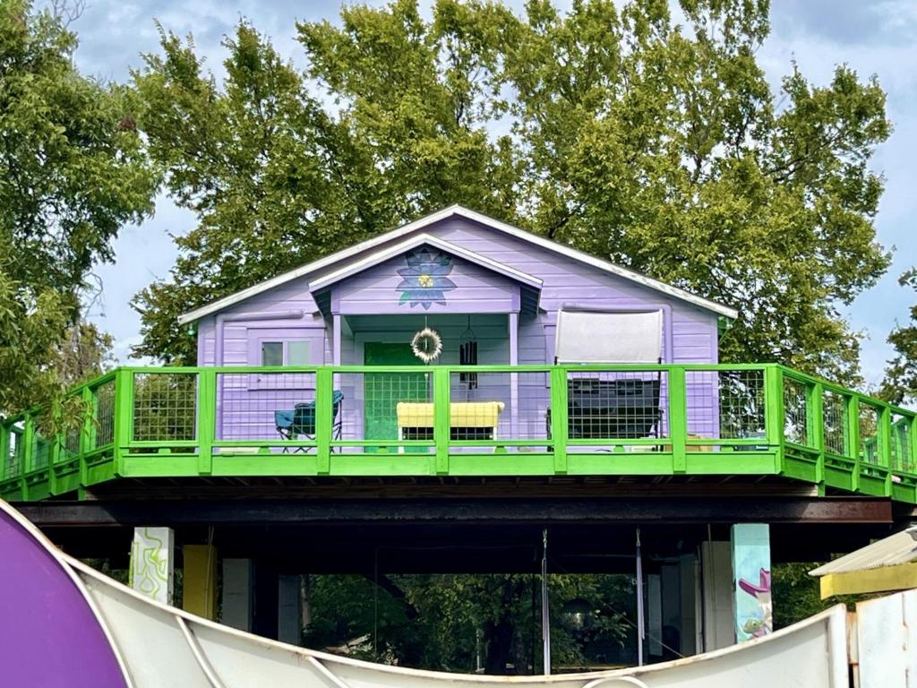 a purple house with a green deck on a ramp at Sky High Treehouse East Austin in Austin