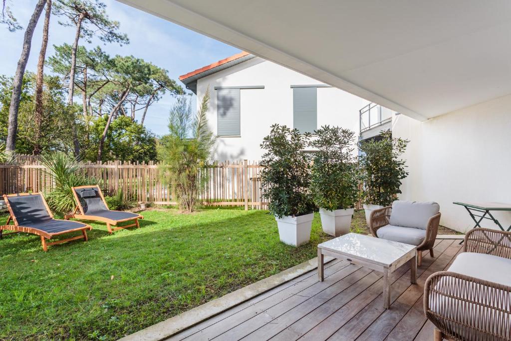d'une terrasse avec des chaises et une table dans la cour. dans l'établissement KARUKERA Bel appartement avec jardin au cœur de Chiberta, à Anglet