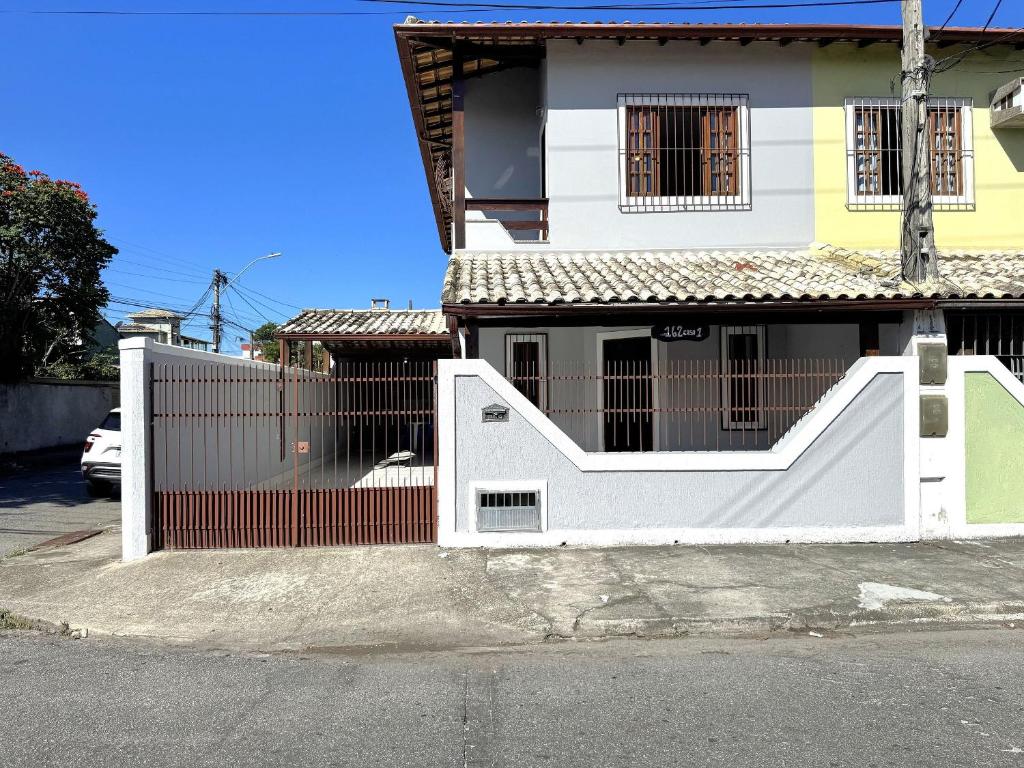a white fence in front of a house at Duplex lindo a 200m da praia | ROTO162 in Rio das Ostras
