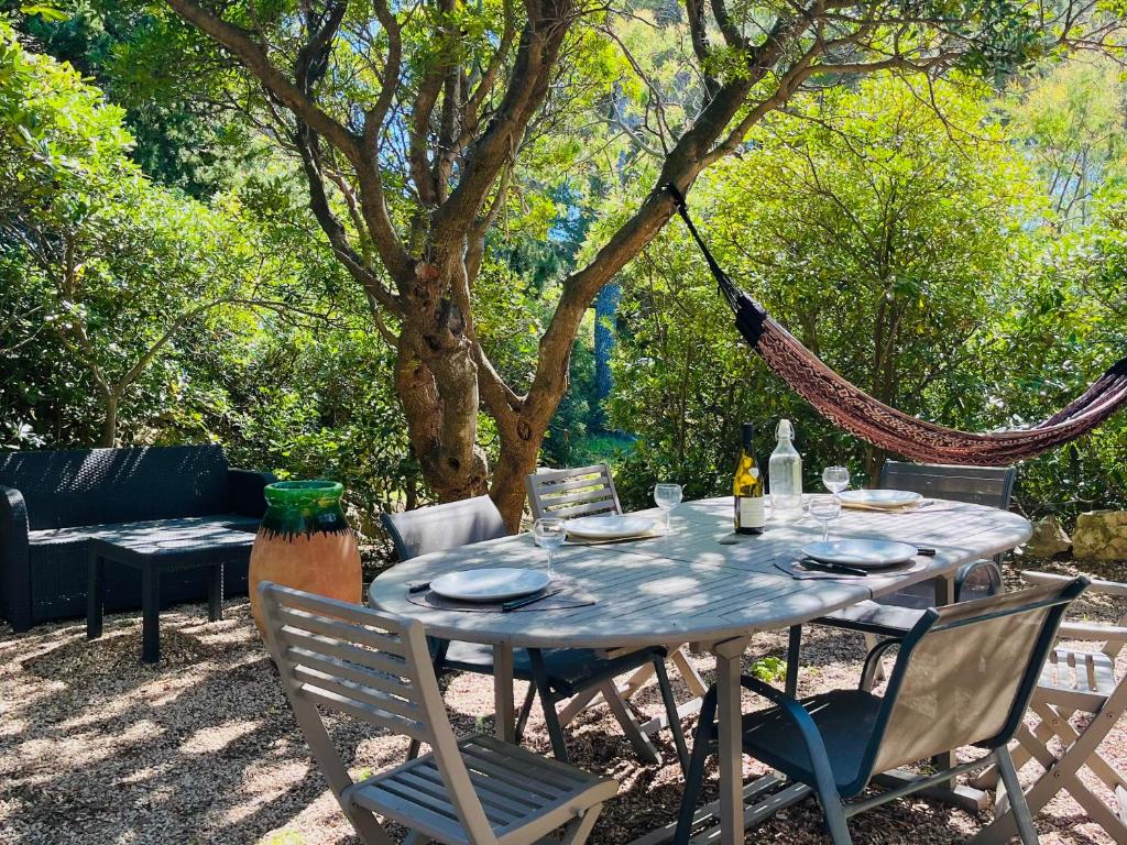 - une table avec des chaises et un hamac dans le jardin dans l'établissement Maison Domaine privé de Port d 'Alon, aux Lecques