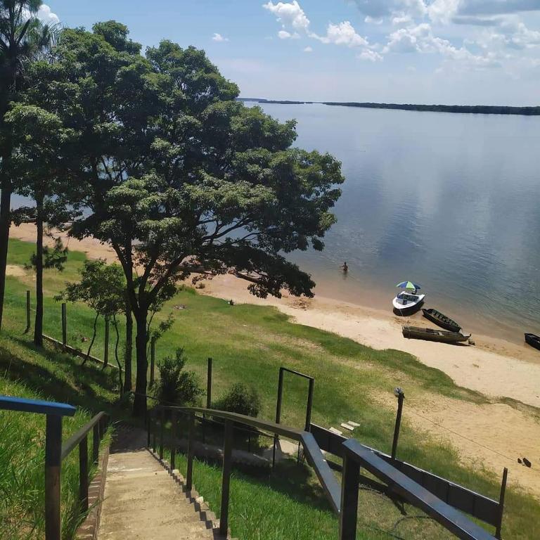 a beach with a tree and a boat in the water at Atardecer Cabaña frente al rio in Ituzaingó