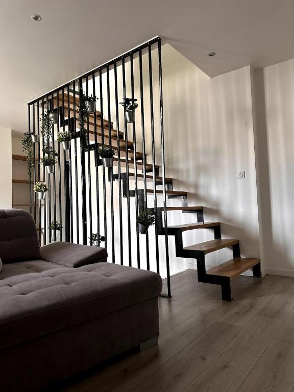 a staircase in a living room with a couch at Charmante maison de ville aux portes de Dole in Crissey
