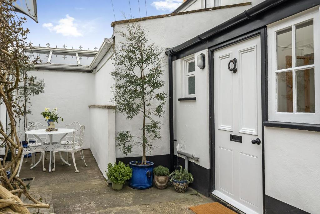 a patio with a door and a table with a tree at Meads Cottage in Charmouth