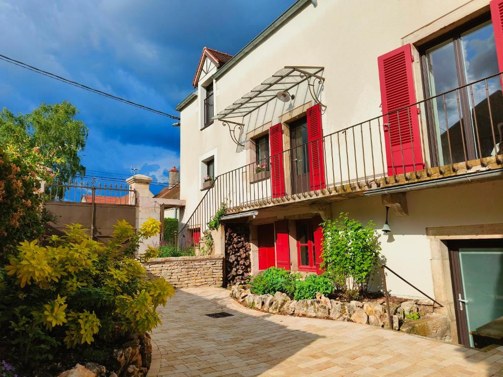 a white house with red shutters and a courtyard at Gîte et studio Les Grands Crus in Morey-Saint-Denis