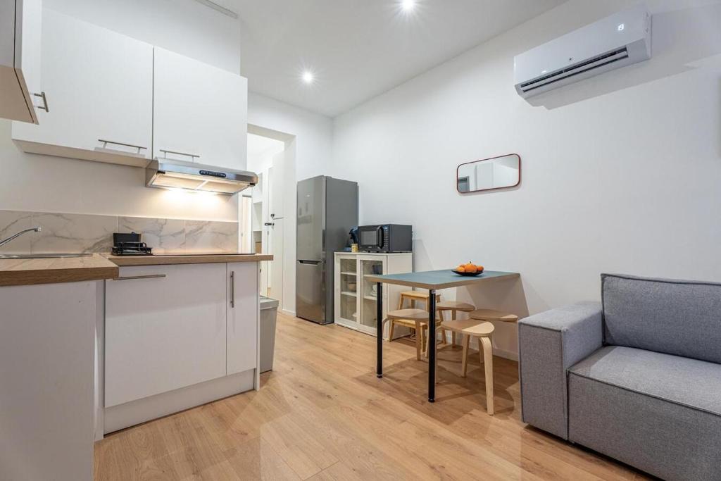 a kitchen and living room with a table and a couch at L'ARCADE SECRETE Appartement climatisé, Jacuzzi, Borne d'arcade Bordeaux centre in Bordeaux
