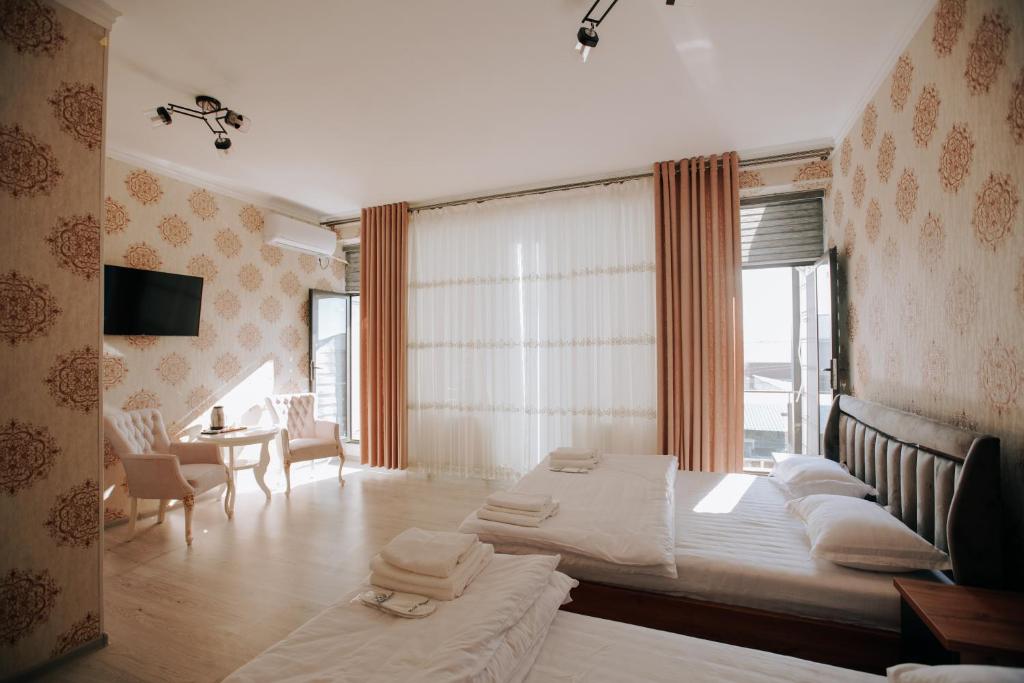 a bedroom with two beds and a table and a window at Best Ali Samira new hotel in Bukhara