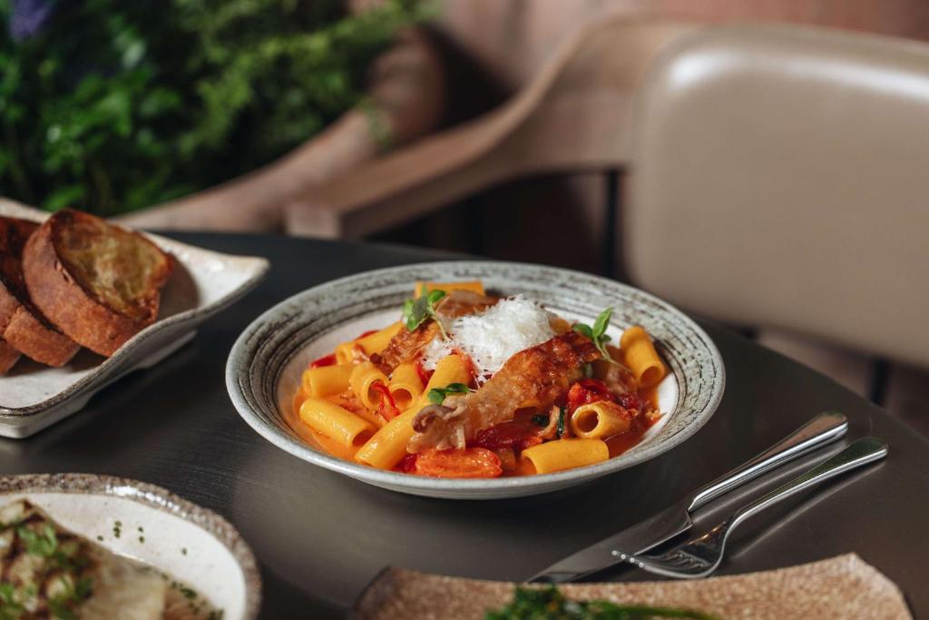 a bowl of pasta with meat and vegetables on a table at Radisson Blu Hotel, London Bloomsbury in London