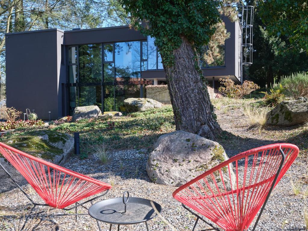 two red chairs and a table in front of a tree at Architektenhaus Hello in Erbach mit High End Interieur zentral aber ruhig in Erbach im Odenwald