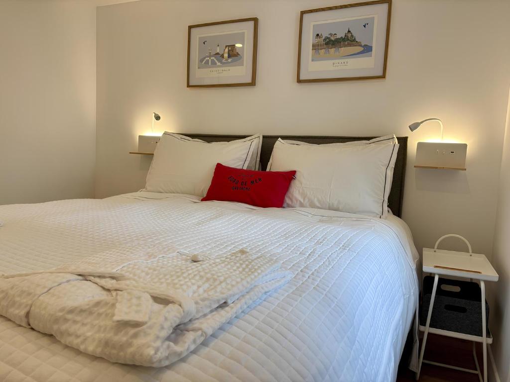 une chambre avec un lit blanc avec un oreiller rouge dans l'établissement Les Thermes- Apartment, à Saint-Malo