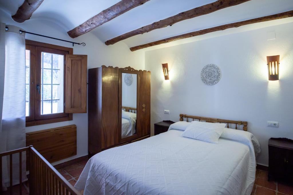 a bedroom with a white bed and a mirror at Casas Rurales El Portillo in Yeste