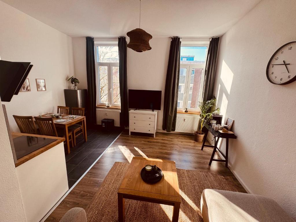 a living room with a table and a clock on the wall at FeWo Nordseebrise in Wilhelmshaven