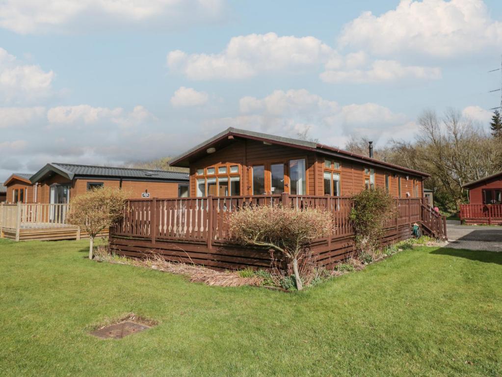 a house with a fence in front of a yard at Gressingham View Lodge in Carnforth
