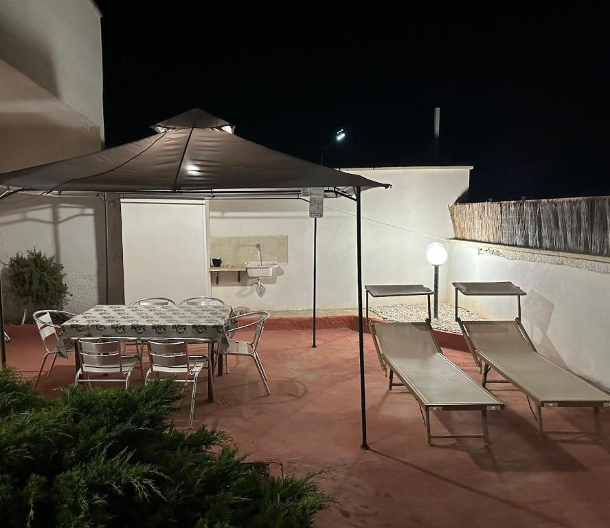 a patio with a table and chairs under an umbrella at Villa Nausica fronte mare - A in Torre Lapillo