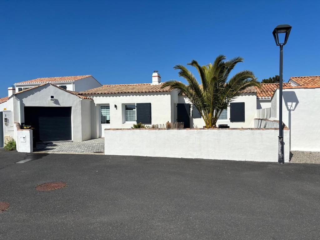une maison blanche avec un garage et un palmier dans l'établissement FLEUR de SEL, à Noirmoutier-en-l'lle