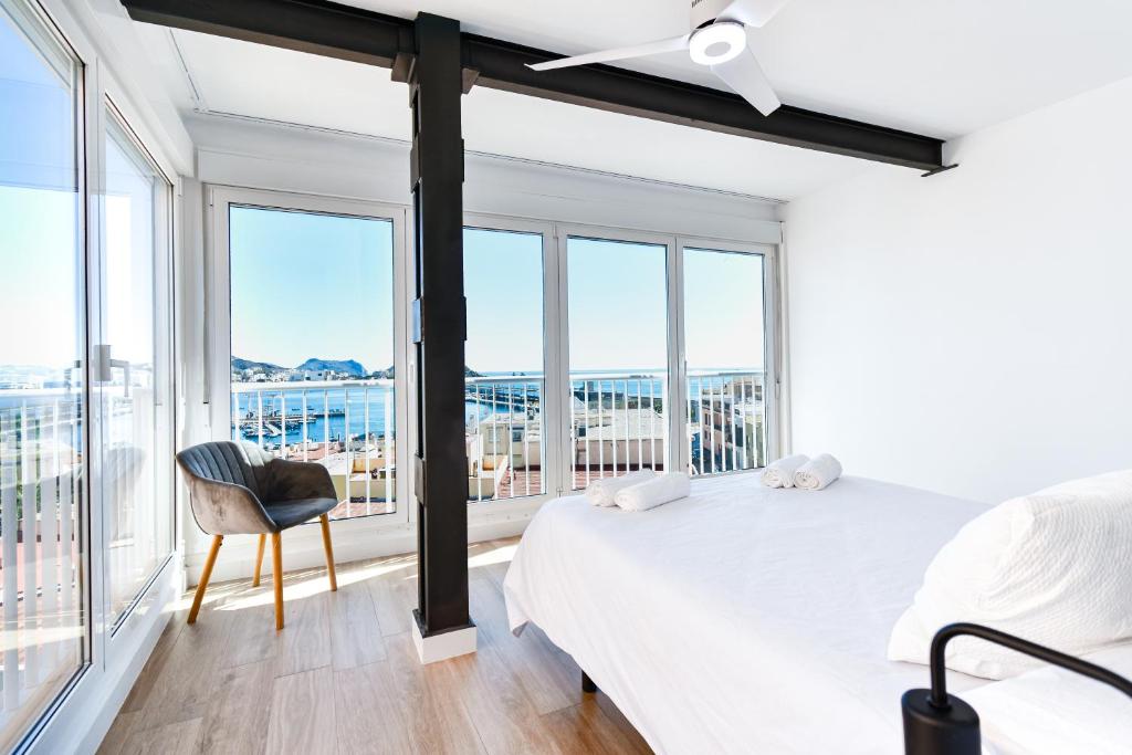 Un dormitorio con una cama y una silla y ventanas. en Lujoso apartamento con vistas al Mar - by Aloha Palma, en Águilas
