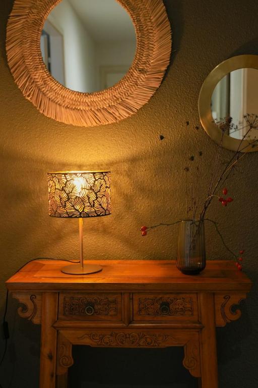 une lampe sur une table en bois avec un miroir dans l'établissement Les Hauts de Bergheim, à Bergheim